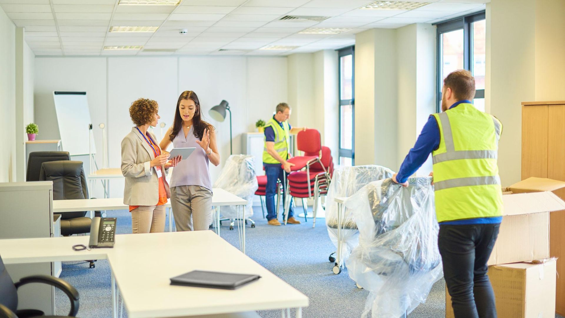 Professional movers relocating office desks chairs and conference room furniture