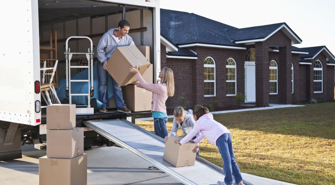 Family unloading boxes and furniture at their new home after relocation