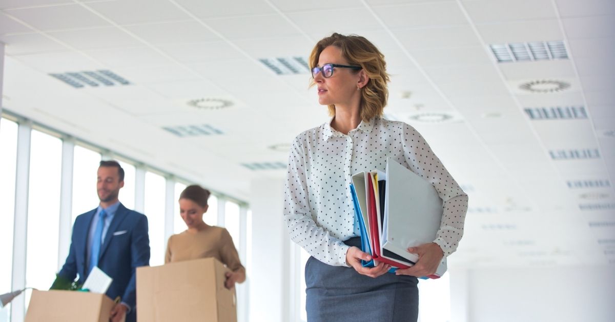 Employees carrying office files and packing boxes while preparing for an office relocation in a modern workplace