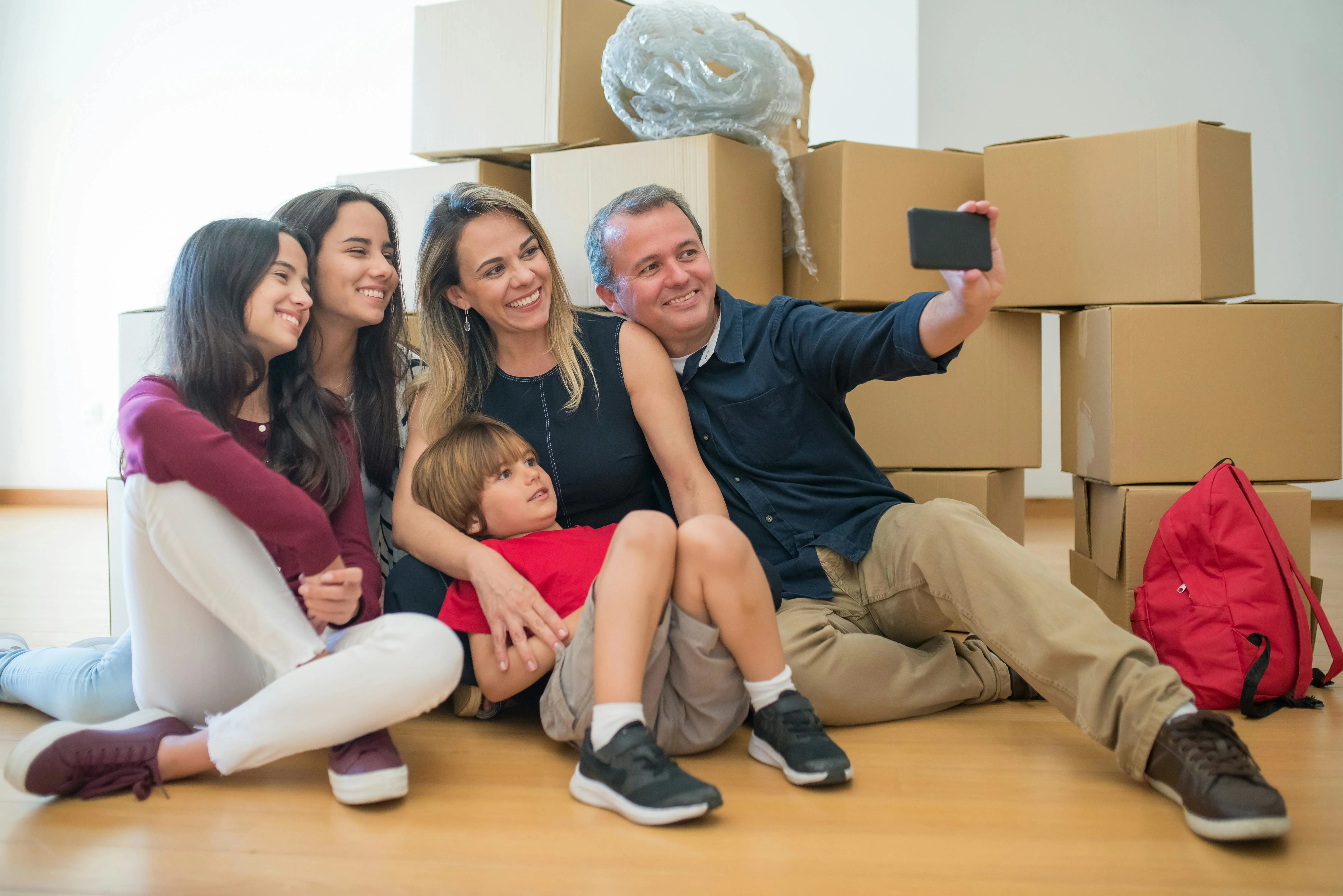 Happy family preparing for a successful move with professional movers and packed boxes outside their home.