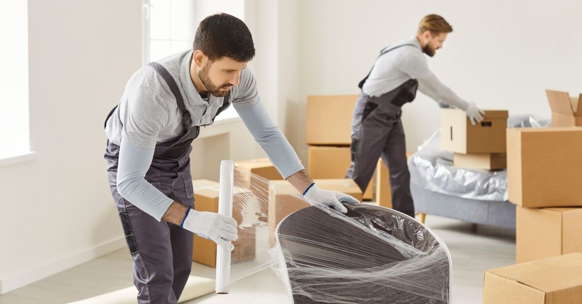Professional interstate movers wrapping furniture and loading belongings safely for transport